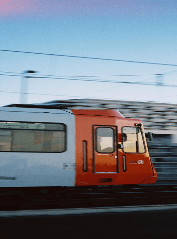Seitenansicht eines orange-weißen Zuges, der mit Bewegungsunschärfe vorbeirast.